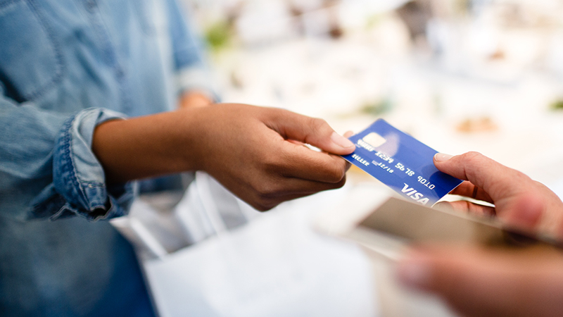 Woman handing off Visa Card to merchant. 