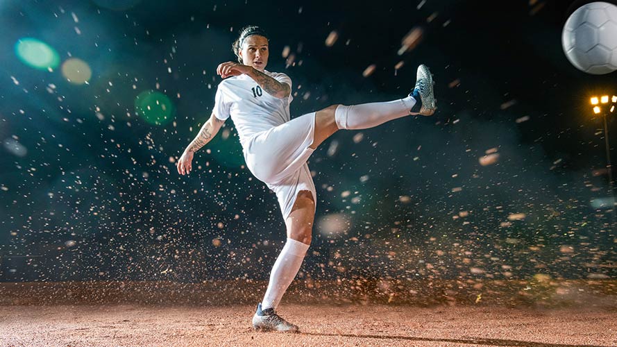 Dzsenifer Marozsán kicking a football.