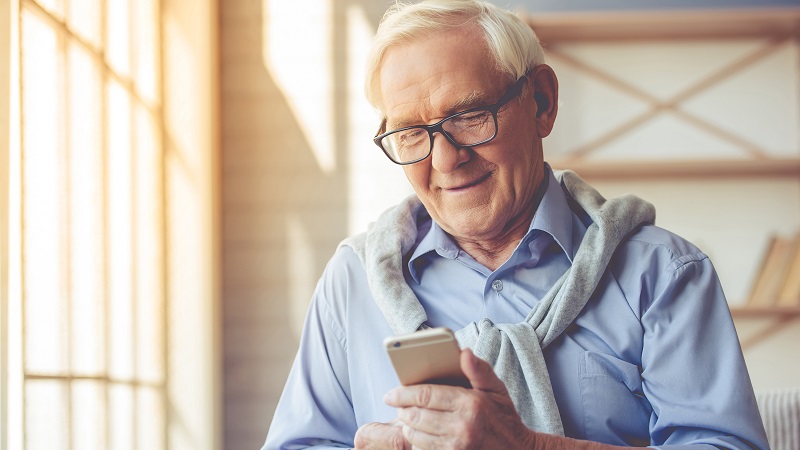 Starszy mężczyzna obsługuje smartfon - grafika ilustracyjna